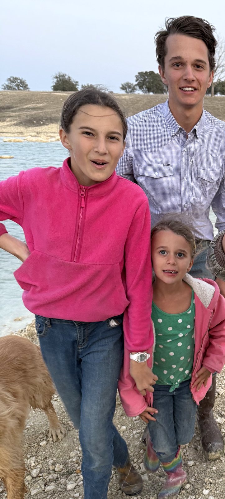 Matthew smiling with two of his sisters by the lake